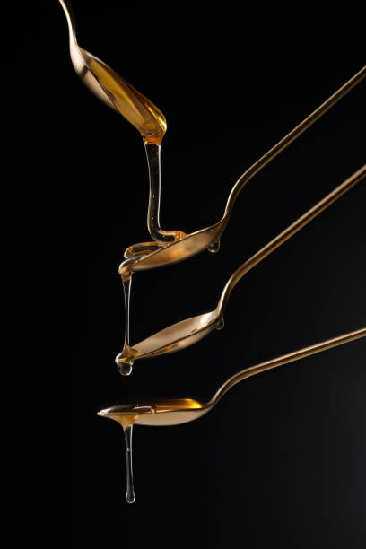 istock Golden spoons with flowing honey on a black background. 2158419784