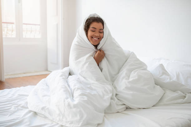 istock Smiling Woman Wrapped in Blanket on Bed 2158420561