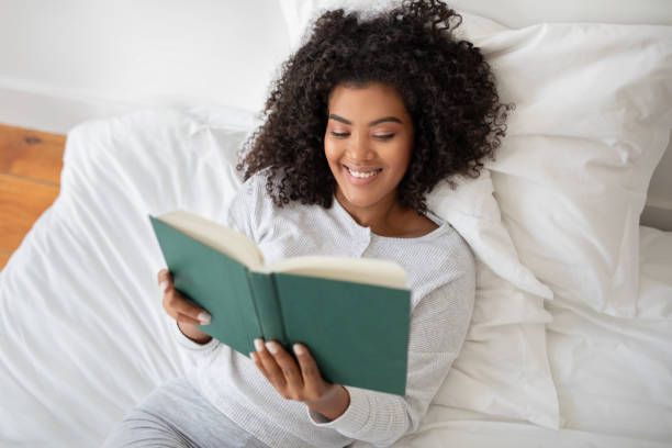 istock Woman Laying in Bed Reading a Book and Smiling 2158420585