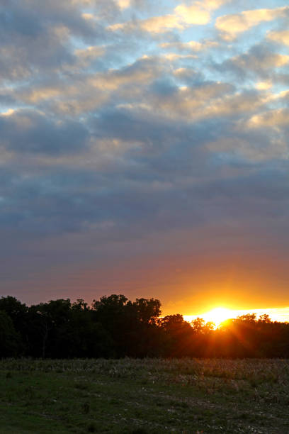 Sunset on the farm in Ohio USA - bright orange looks like fire blazing above the treeline