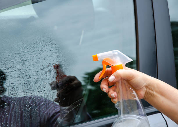 istock Woman spraying car window cleaning solution 2158421916