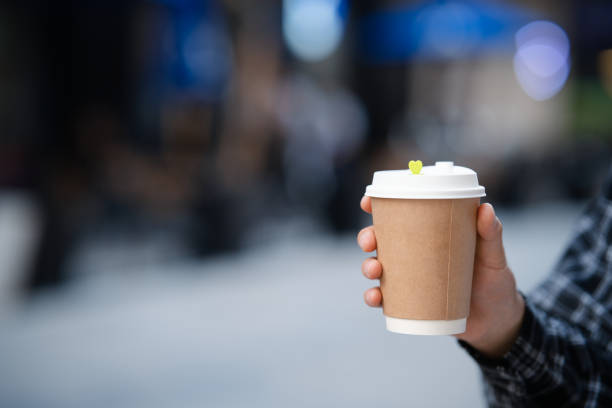 istock Young man holding coffee cup standing on city street 2158428055