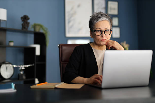 istock Mature professional working on a laptop, reflecting a blend of experience and modern digital competence. 2158428259