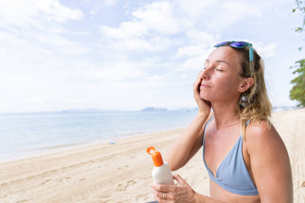 istock Woman Applying Sunscreen on Face at Beach 2158429226