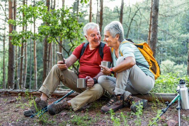 istock Senior couple of hikers using phone in the forest 2158429416