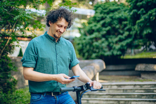 istock Man unlocks an e-scooter with his mobile phone. Man holding phone on electric kick scooter 2158430640
