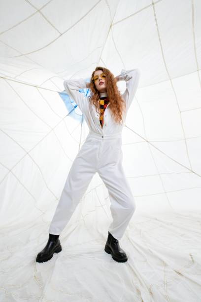 istock Young Woman Posing in White Jumpsuit Against White Background 2158432109