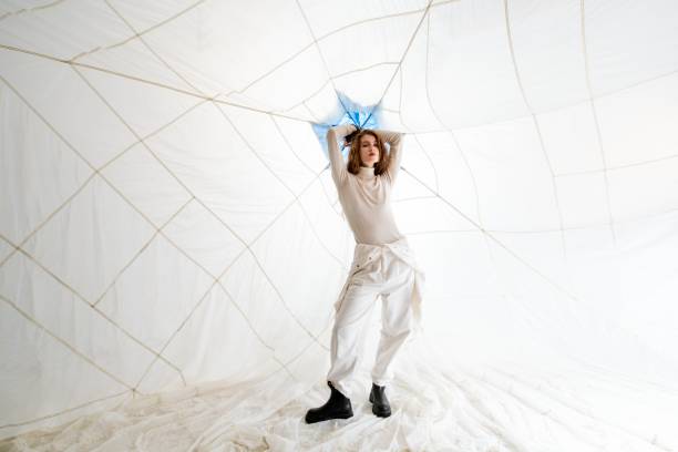 istock Woman Posing in White Clothing Against a White Background With String Lights 2158432647