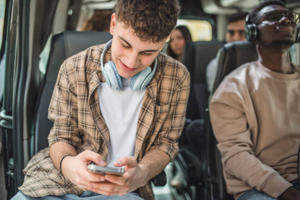 istock A cheerful young man uses a mobile phone while his black friend sitting next to him listens to music on wireless headphones 2158432733