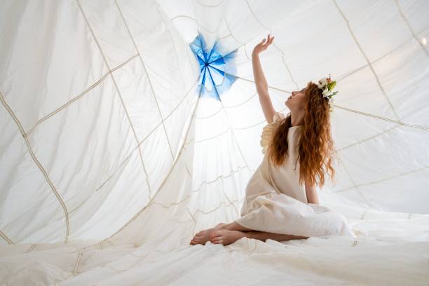 istock Young Woman Reaching Up Inside Large White Fabric Structure 2158432877