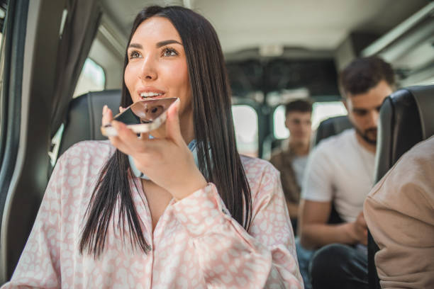 istock A female student uses a mobile phone to send a voice message while traveling on a bus. She travels by bus with a group of other students 2158433765