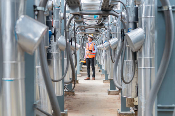 Engineer inspects water heater pump system and hot water tank on industrial roof