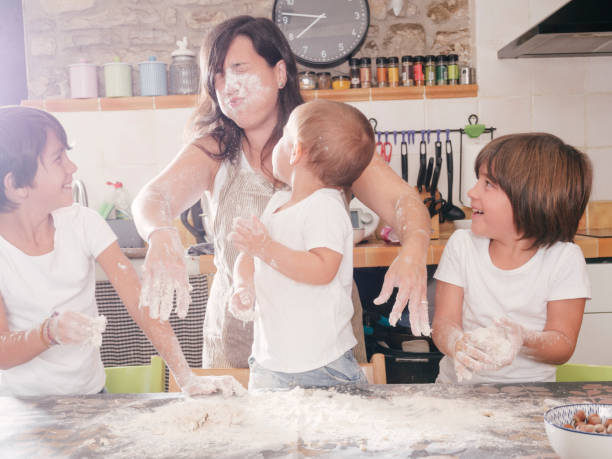 istock Sons throw flour in mother's face while preparing cake recipe in the kitchen. 2158439014