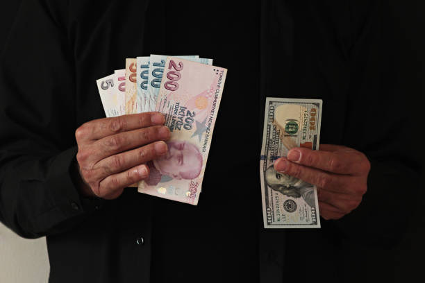 istock Hands of adult man holding American 100 Dolar and Turkish Banknotes 2158440708