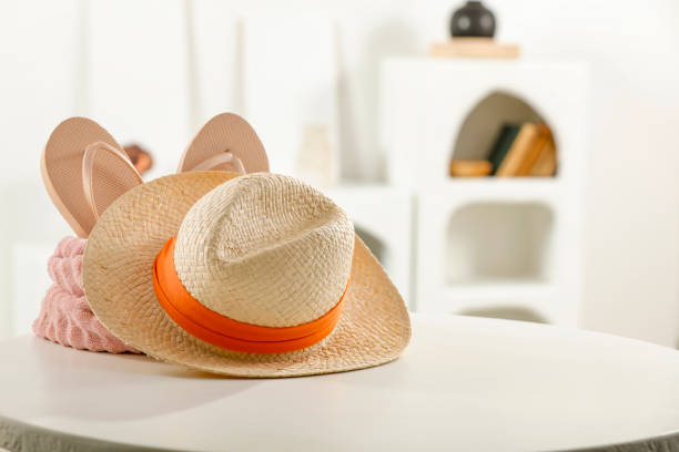 Collection of fedora or summer hats displayed neatly in square sections on a dark wooden panel wall, illuminated by overhead spotlights. Fashion and style