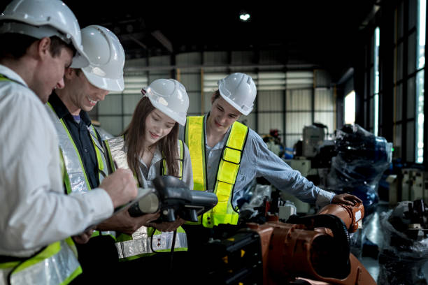 istock team engineers inspecting on machine with smart tablet. Worker works at heavy machine robot arm. The welding machine with a remote system in an industrial factory. Artificial intelligence concept. 2158442476