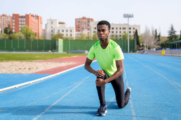 istock Aafrican man in a green shirt is kneeling on a track 2158442843