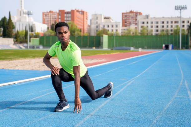istock A african man in a green shirt is stretching on a track 2158442855
