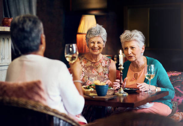 istock Conversation, wine and smile with elderly friends in home for bonding, laugh and relax. Retirement, celebration and happiness with senior people and lunch for social, memory and support together 2158442964