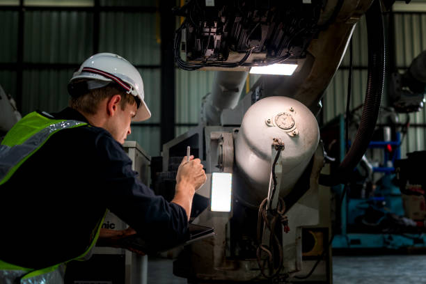 istock team engineers inspecting on machine with smart tablet. Worker works at heavy machine robot arm. The welding machine with a remote system in an industrial factory. Artificial intelligence concept. 2158444711