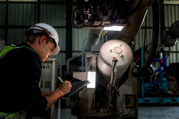istock team engineers inspecting on machine with smart tablet. Worker works at heavy machine robot arm. The welding machine with a remote system in an industrial factory. Artificial intelligence concept. 2158444974