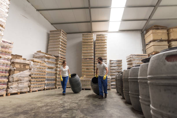 Couple of workers moving barrels in olives factory while talking