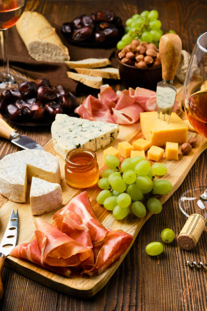 istock Cheese plate with prosciutto, grapes, honey, dates, crackers, nuts and wine 2158456267