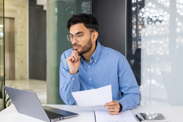 istock Business professional working at desk with laptop, document, and tablet in modern office 2158460435