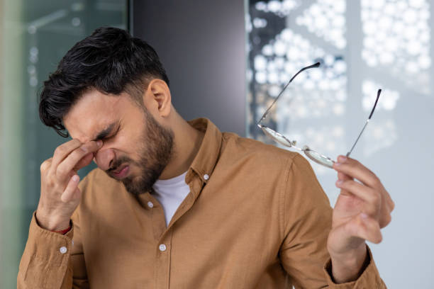 istock Young man experiencing eye strain while removing eyeglasses in office environment 2158460705