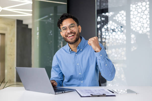 istock Happy professional celebrating success at work with laptop in modern office 2158461937