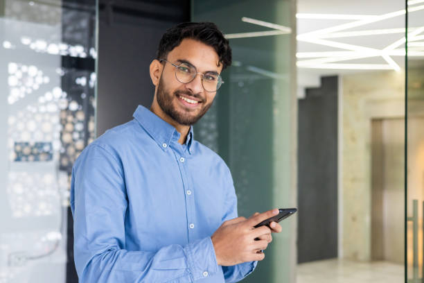 istock Smiling businessman using smartphone in modern office building 2158466543