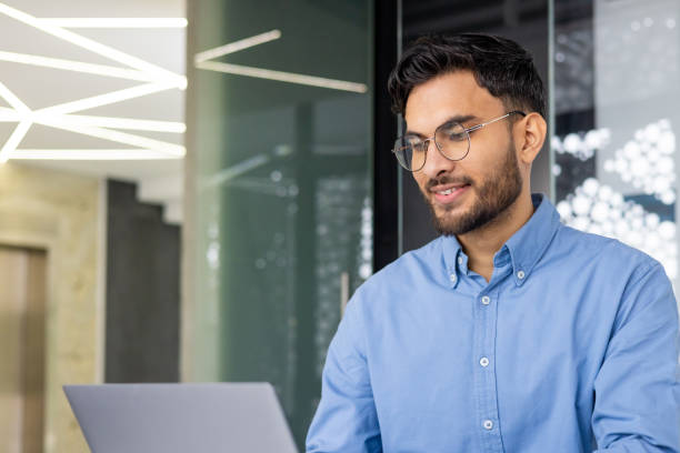 istock Young businessman working confidently on laptop in modern office environment 2158467868