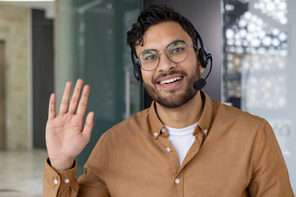 istock Friendly customer service representative with headset waving and smiling in modern office 2158468637
