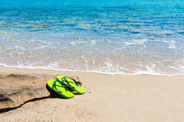 istock Pair of flip flops on a sandy beach 2158469030