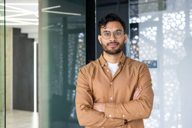 istock Confident young man with glasses standing and smiling in a modern office environment 2158470149
