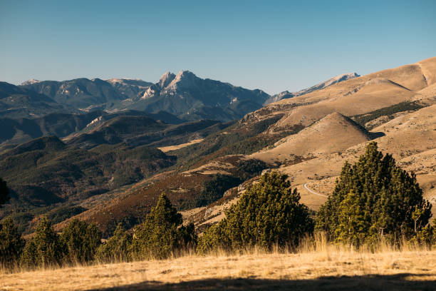 Sunlight highlights the rugged beauty of mountains and gentle slopes in the landscape.