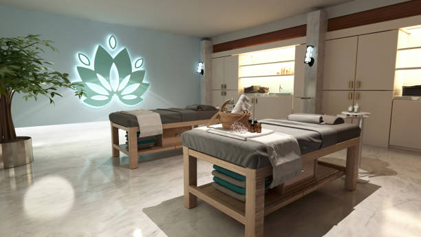 This image showcases the interior design of a spa featuring two wooden massage tables, a decorative lotus flower, and a relaxing atmosphere. The spa features white walls, natural light, and a sense of tranquility.