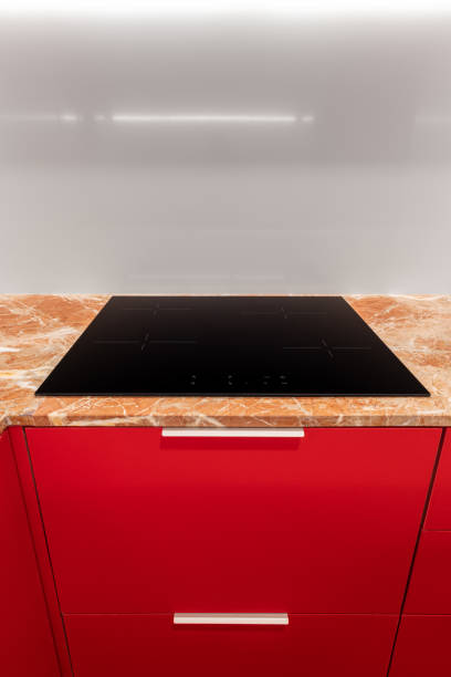 A Kitchen With Red Cabinets And A Black Stove Top