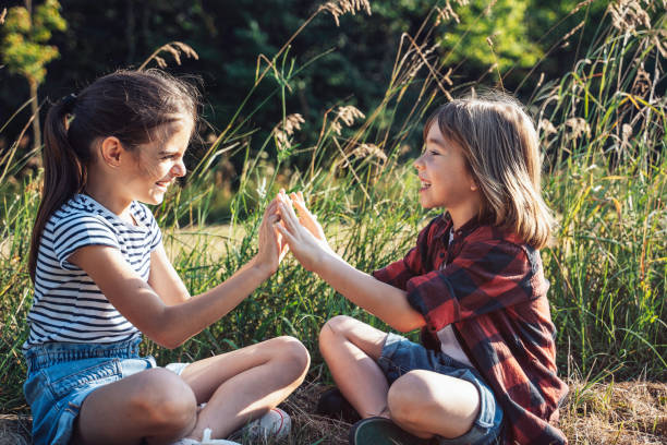 istock Two children playing hand game in grassy field setting 2158478913