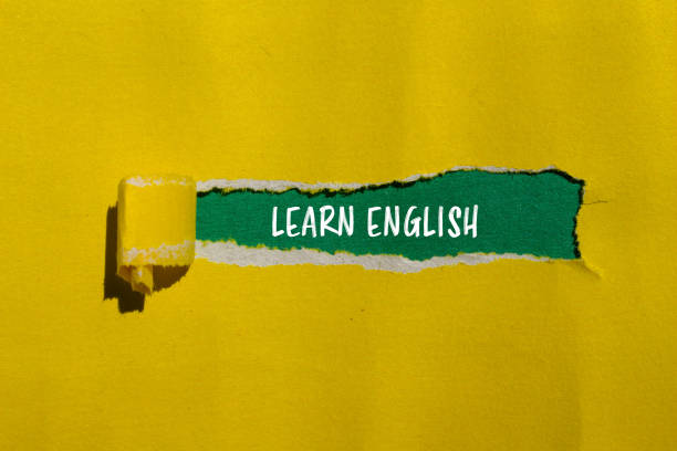 istock Learn english message written on ripped yellow paper with green background 2158479529