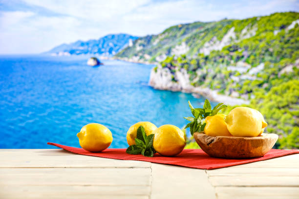 istock Yellow lemons scattered on wooden table top with blur  seascape background. 2158480203