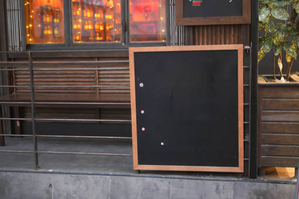 istock Empty wooden blackboard mockup standing outdoors in front of cafe 2158482247