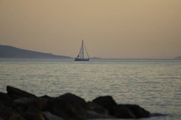 Alone sailboats at sunset. Atmospheric seascape with reflection