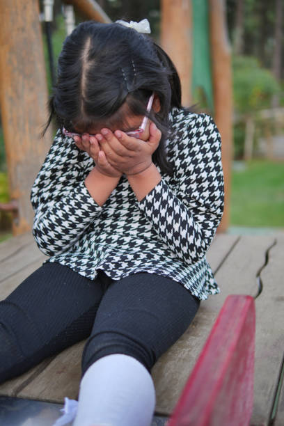 istock a upset child girl cover her face with hand 2158486028