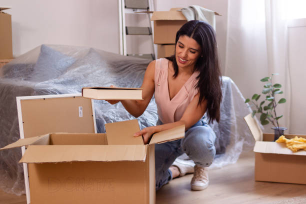 istock Young woman putting things in a donation box while moving out 2158489075