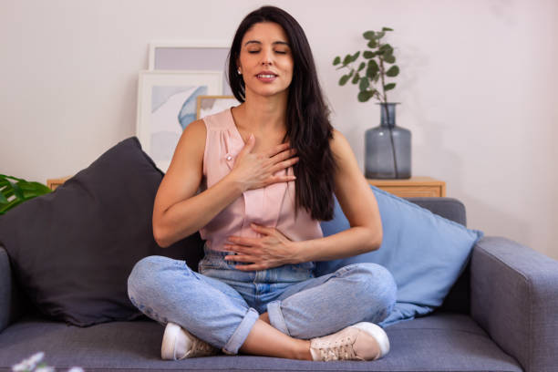 istock Young woman practicing deep breathing exercise at home 2158489412