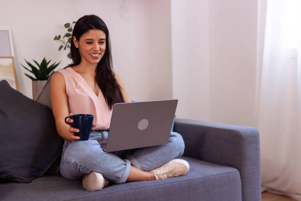 istock Happy young woman enjoying a coffee break while working remotely from home on a laptop 2158489437