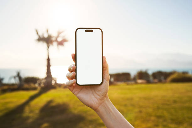 istock Young woman showing mobile phone blank white screen on Marina Background 2158492321