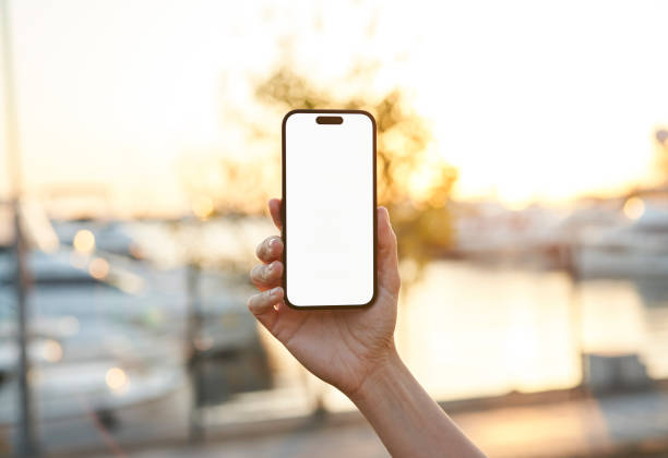 istock Young woman showing mobile phone blank white screen on Marina Background 2158492328