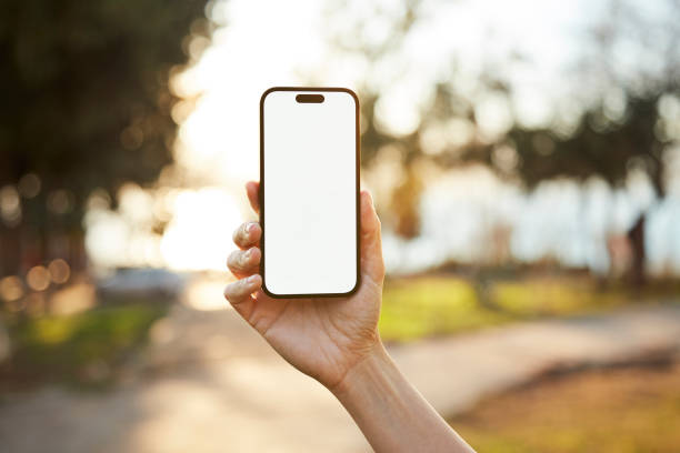 istock Young woman showing mobile phone blank white screen on Marina Background 2158492347